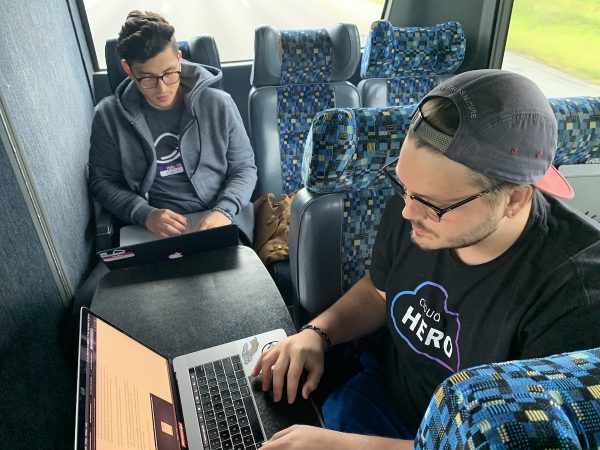 Photo: David Castañeda and Justin Linn working on their laptops on StartupBus Florida, July 2019.